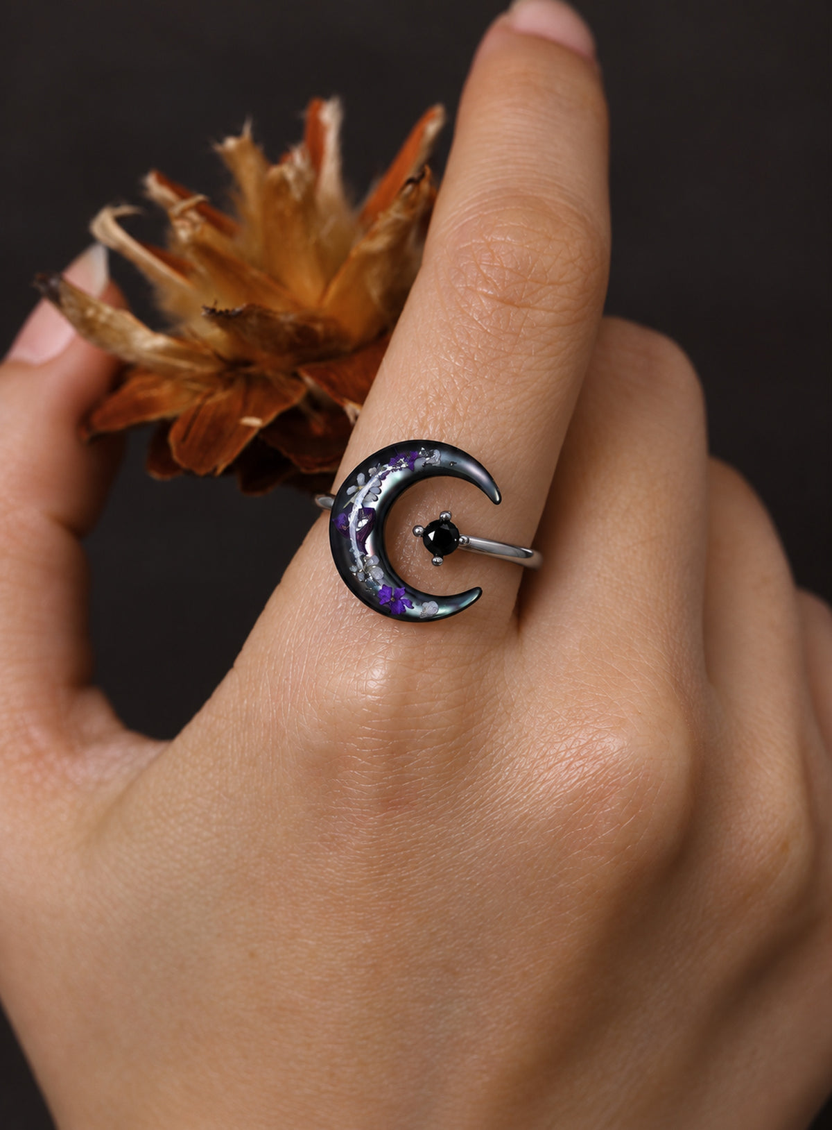 Silver-finish open ring with a dark crescent, purple pressed flowers and a black stone. (Silver)