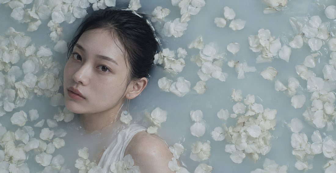 Model wearing Aquamarine Drop Earrings among white petals