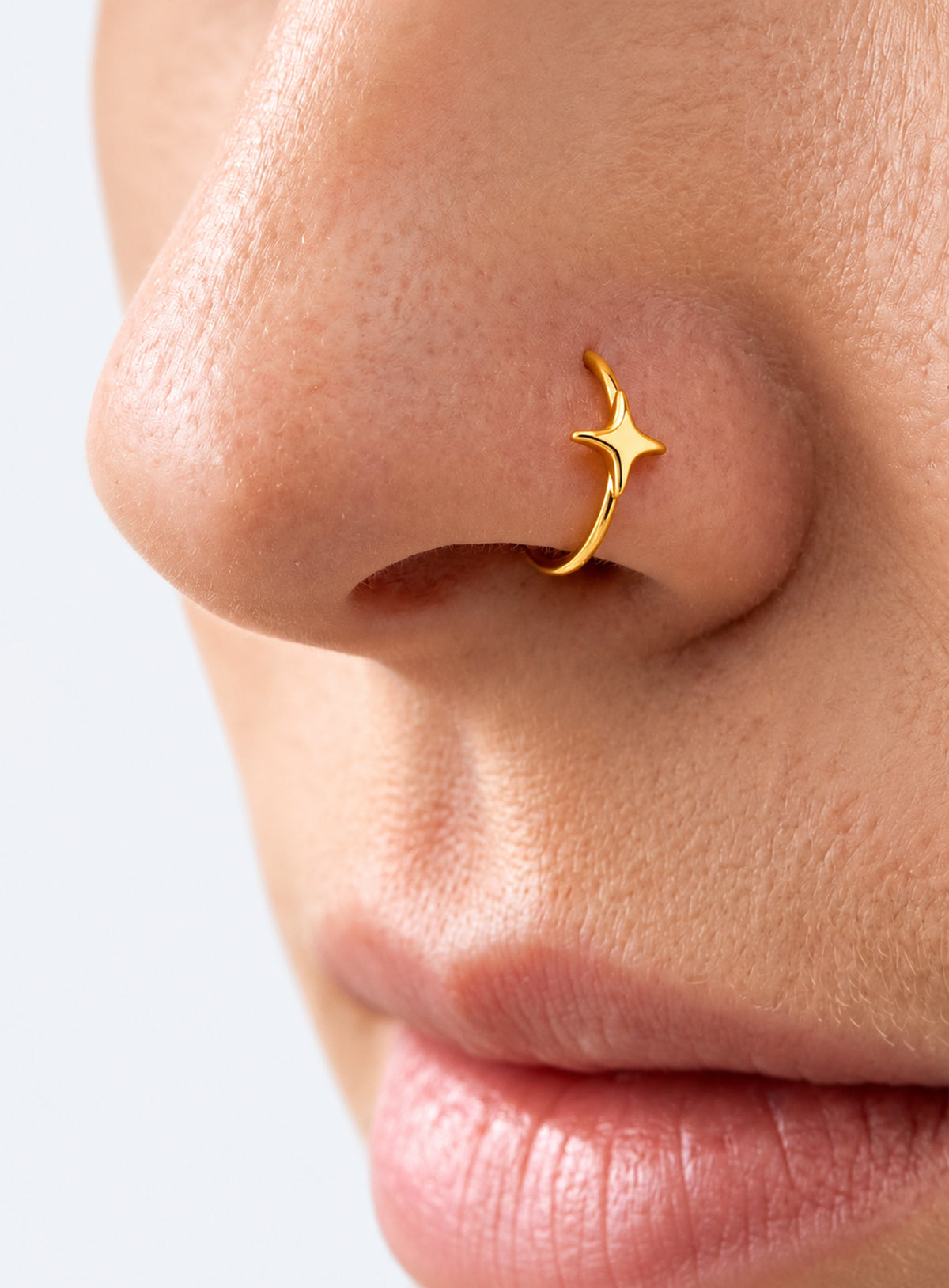 Star detail nose hoop with hinged clicker closure, shown in a studio product photo (Gold)