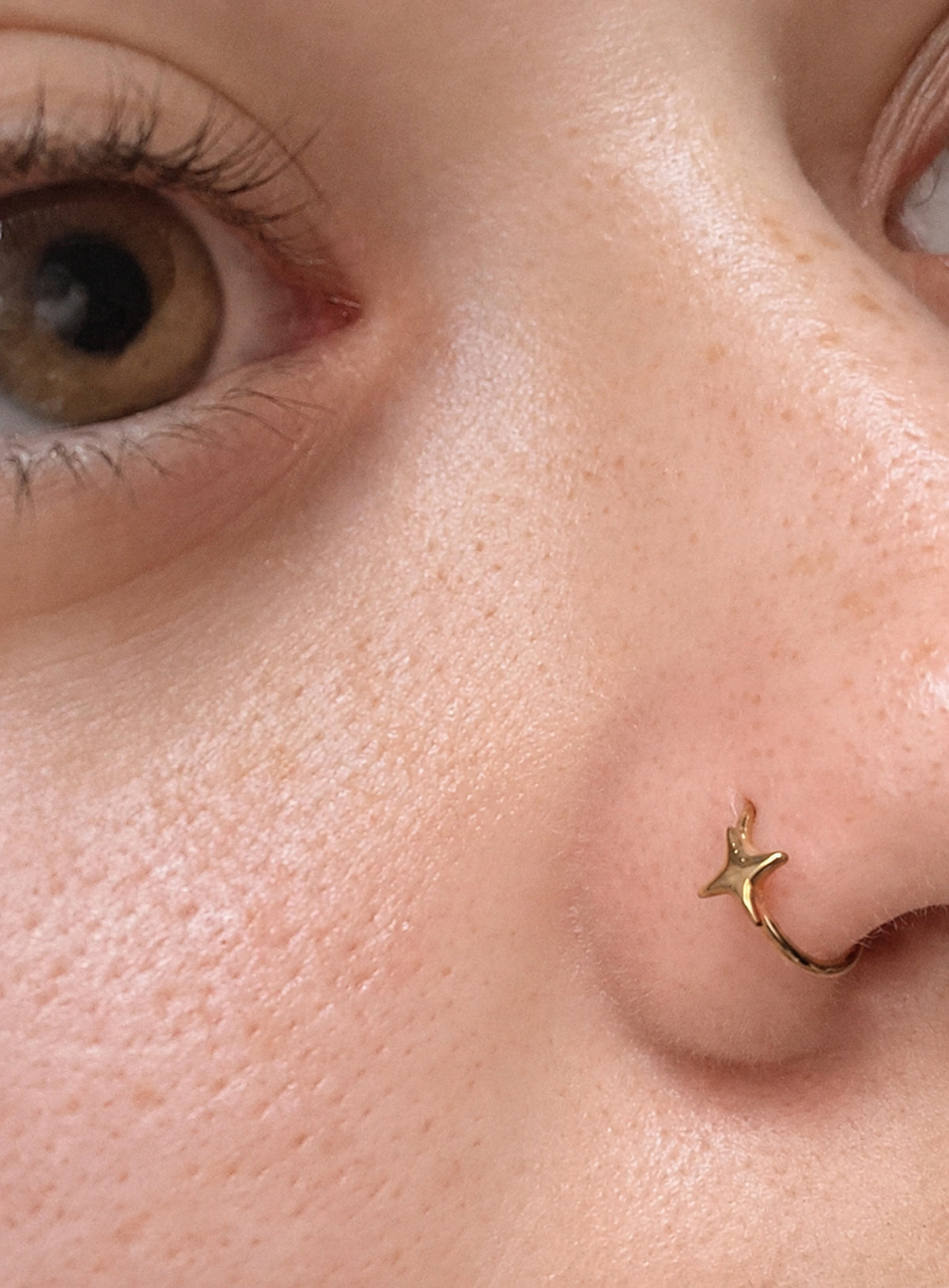 Star detail nose hoop with hinged clicker closure, shown in a studio product photo (Gold)