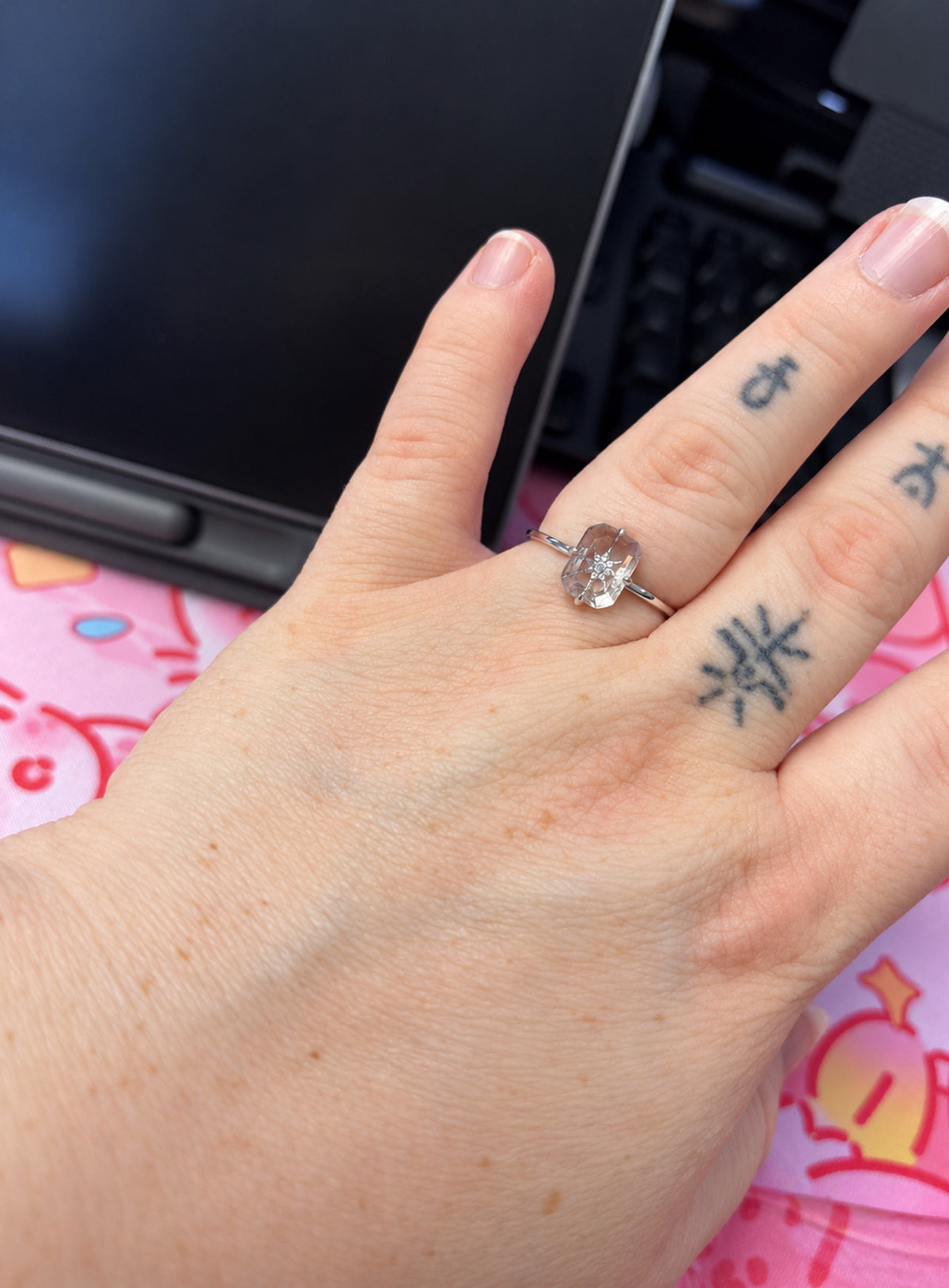 Slim silver or gold ring with clear rectangular centre, starburst motif and small clear accents