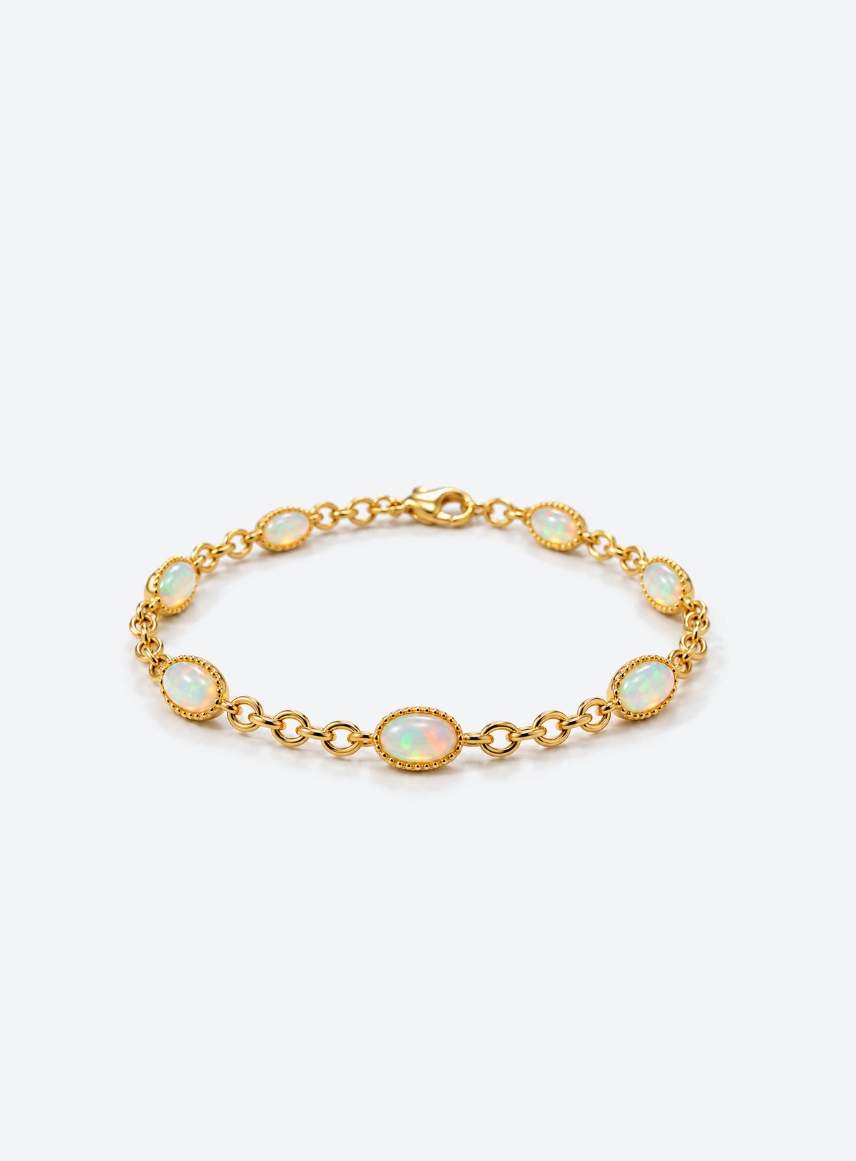 Gold-toned link bracelet with oval white opals, fine beaded bezel edges, and connecting chain links.