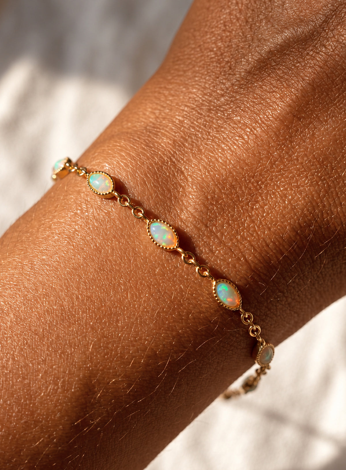 Gold-toned link bracelet with oval white opals, fine beaded bezel edges, and connecting chain links.