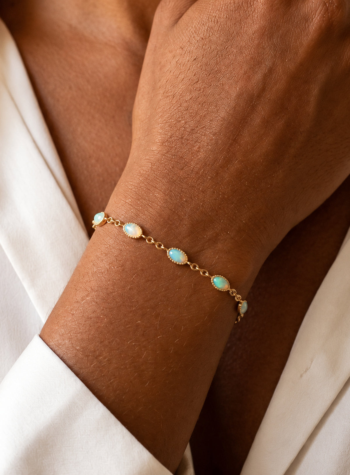 Gold-toned link bracelet with oval white opals, fine beaded bezel edges, and connecting chain links.
